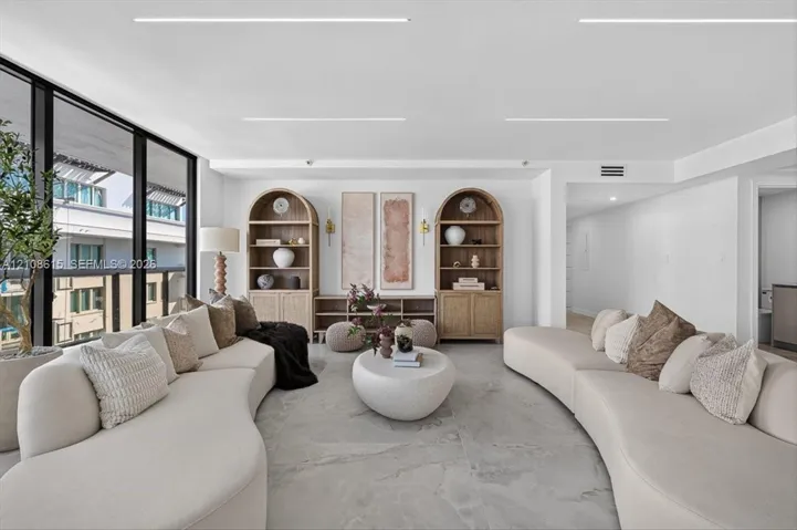 Floor-to-ceiling windows with dark framing, custom built-in arched wood shelving, and large-format stone-finish tile flooring