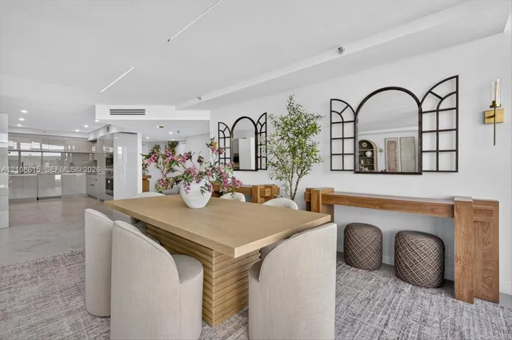 Open-concept interior featuring recessed lighting, sleek cabinetry, neutral tile flooring, and minimalist wall-mounted gold-toned light fixtures