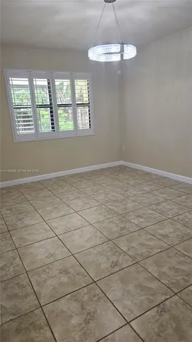 Ceramic tile flooring, crown molding, multi-panel window with plantation shutters, and a circular crystal pendant light fixture