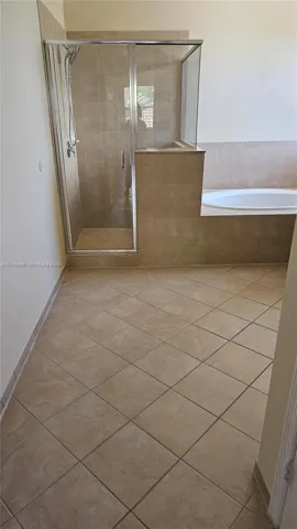 Ceramic tile flooring, built-in soaking tub with a tiled surround, and a walk-in glass-enclosed shower with a handheld showerhead