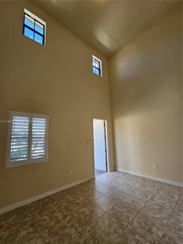 High-volume ceilings with two levels of windows, tile flooring, and interior window shutters