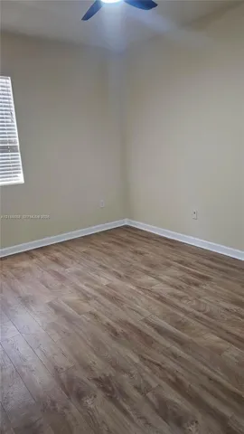 Neutral wall tones, wood-finish flooring, and a ceiling-mounted fan with integrated lighting