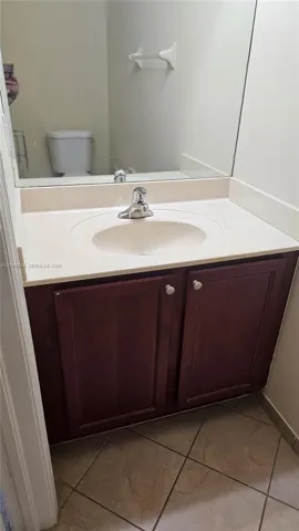 Bathroom vanity featuring a dark wood-finish cabinet, integrated basin, countertop with matching backsplash, and tile flooring