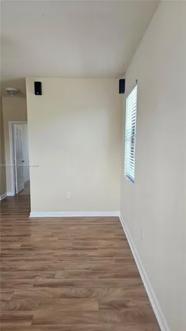 Interior space featuring wood-finish flooring, a neutral wall palette, and a window with horizontal blinds