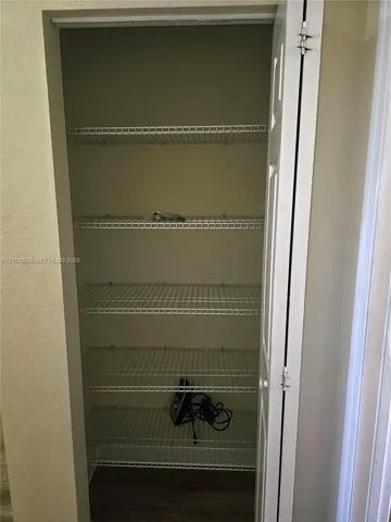 Storage closet featuring five tiers of white wire shelving and a hinged six-panel door