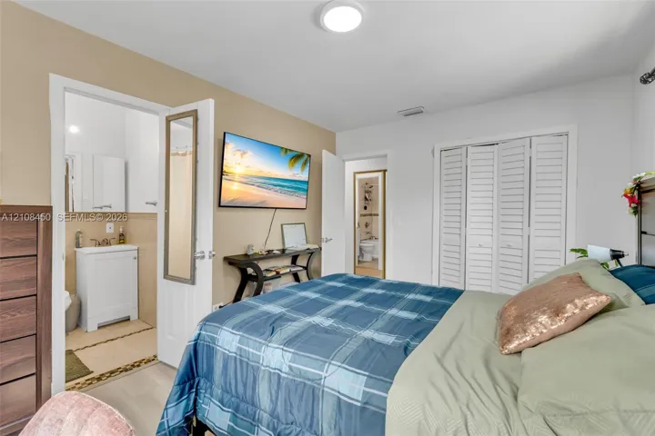Room featuring wood-finish flooring, white louvered closet doors, flush-mount ceiling lighting, and neutral wall tones