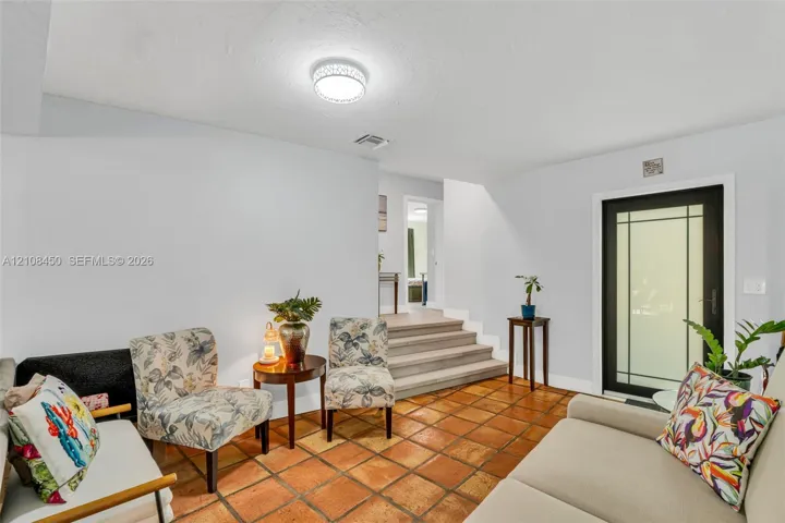 Terra cotta tile flooring, glass-paneled exterior door, and multi-level floor plan featuring stepped elevation