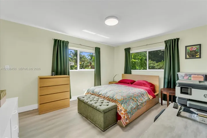 Bedroom featuring light wood-finish flooring, dual sliding windows, and a flush-mount ceiling light fixture