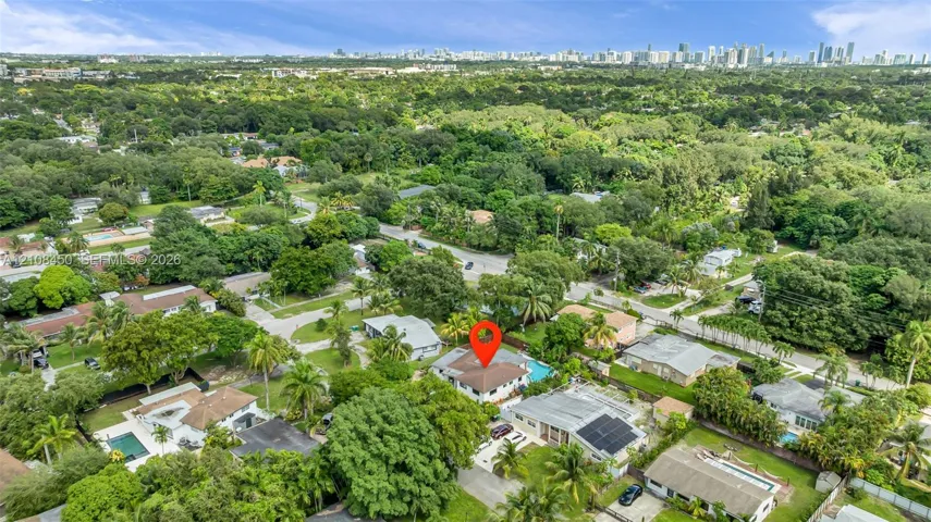 Aerial perspective of property featuring an inground swimming pool, concrete driveway, and expansive mature landscaping