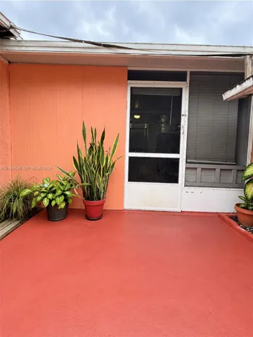 Covered patio featuring a solid-surface floor, vertical panel siding, and a screen door with a transom window