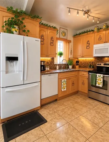 Kitchen featuring wood cabinetry, stone-finish countertops, stainless steel range, white French-door refrigerator, and under-cabinet lighting