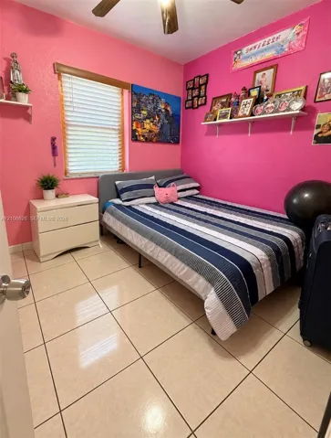 Ceramic tile flooring, horizontal slat window blinds, ceiling fan, and wall-mounted shelving