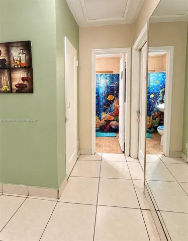 Hallway featuring large-format ceramic tile flooring, full-length wall mirror, and solid-core interior doors