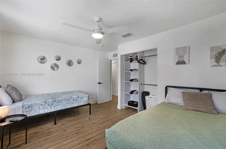 Wood-finish flooring, ceiling fan with integrated lighting, and built-in closet shelving