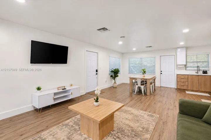 Open-concept interior featuring wood-finish flooring, recessed lighting, and a kitchenette with wood-finish cabinetry