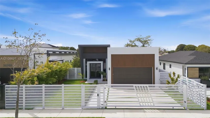 Modern architectural exterior featuring a wood-panel accent wall, dual-tone facade, flat roofline, and a contemporary motorized white privacy gate