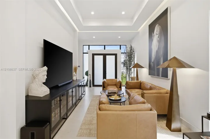 Tray ceiling featuring integrated recessed lighting, smooth finish walls, and glass-paneled double entry doors with dark metal framing