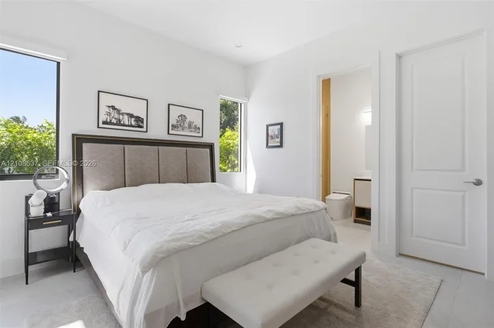 Light-filled space featuring large windows, neutral stone-finish flooring, recessed lighting, and a solid-core interior door