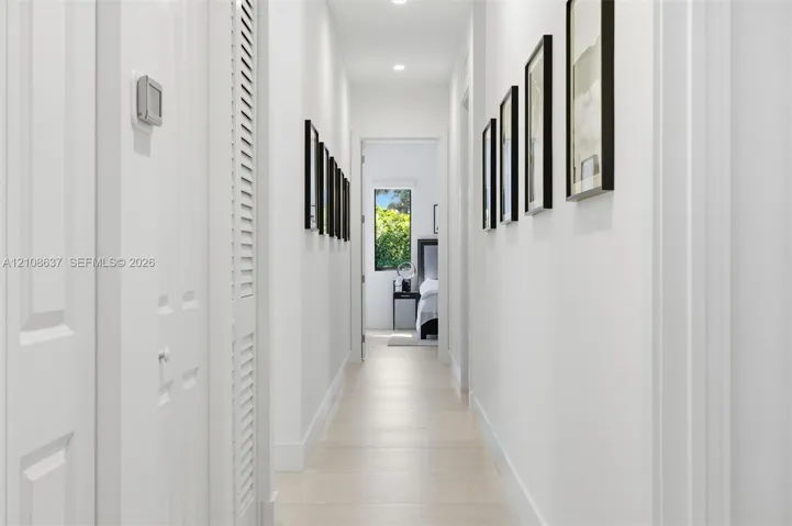 Hallway featuring light-toned tile flooring, recessed ceiling lighting, and louvered-style bi-fold closet doors
