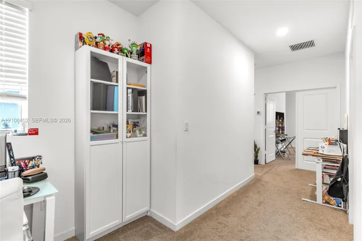 White built-in cabinetry with glass-paneled upper doors, wall-to-wall carpeting, and recessed ceiling lighting