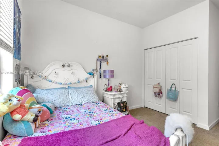 Room featuring neutral-toned carpeting, high ceilings, and a double-door closet