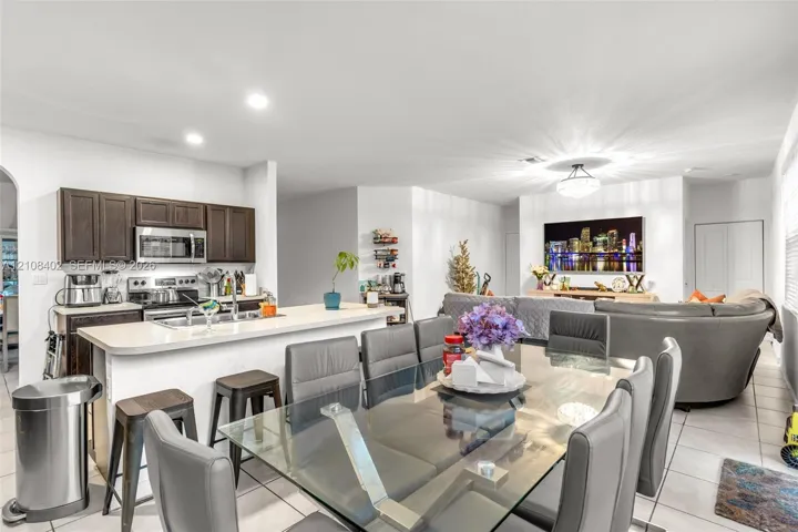 Kitchen featuring dark wood cabinetry, an integrated breakfast bar, and stainless-steel appliances, complemented by tile flooring and recessed lighting