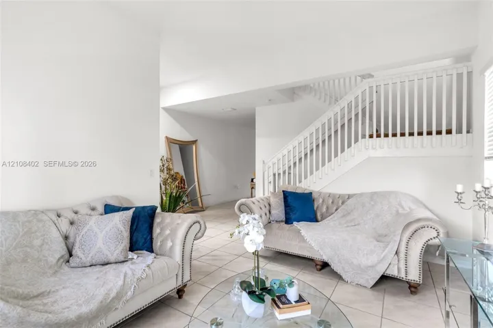 Open-concept interior featuring large-format ceramic tile flooring and a staircase with white vertical balusters