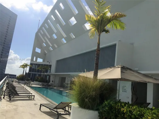 Rooftop swimming pool featuring a concrete deck, architectural geometric screening, and integrated landscaping planters