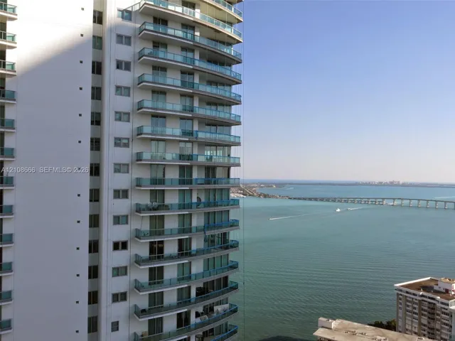High-rise building exterior featuring tiered concrete balconies with glass railings and floor-to-ceiling windows