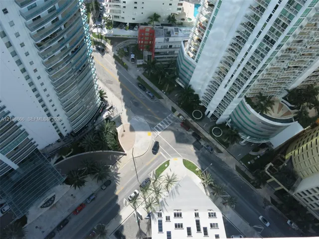 High-rise urban setting featuring tiered glass balconies, multi-story structural architecture, palm tree landscaping, and paved street-level infrastructure