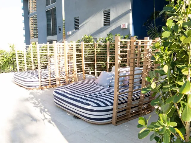 Outdoor terrace featuring stone tile flooring, custom slatted wood privacy structures, and integrated landscaping