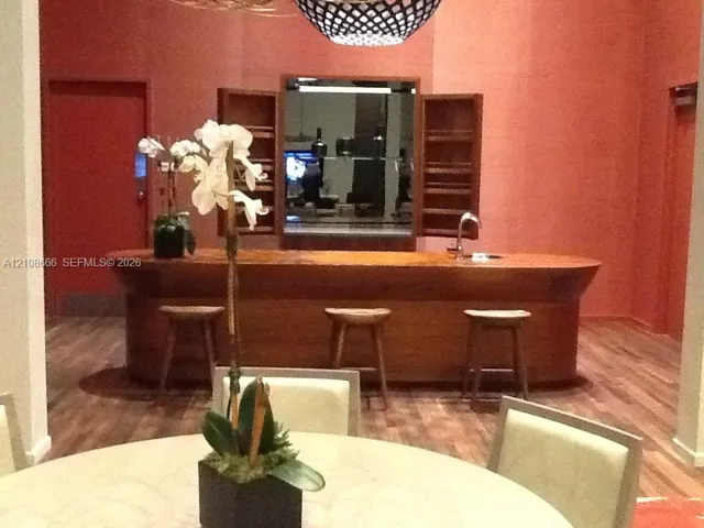 Custom wood-finished bar featuring a curved design, built-in shelving, a stainless steel sink, and wood-finish flooring