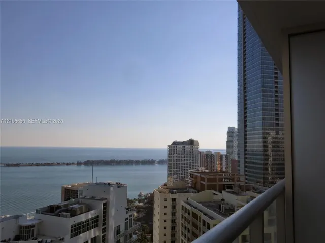 Private balcony with a metal railing, showcasing an expansive waterfront and urban skyline