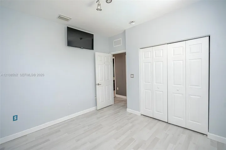 Light-toned wood-finish flooring, six-panel interior doors, and bi-fold closet doors with recessed panels