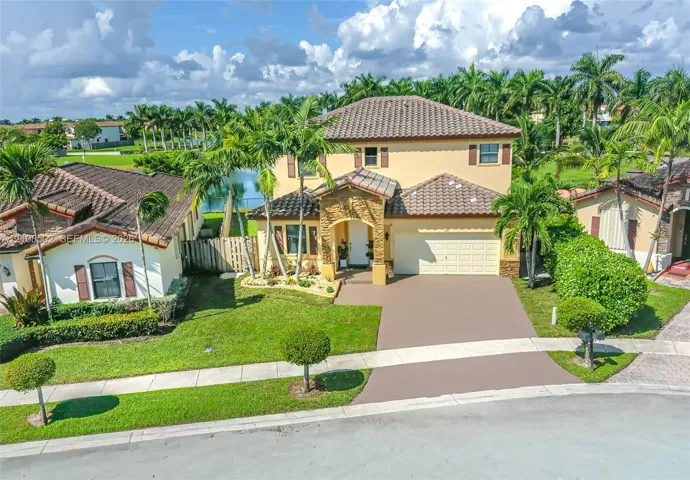 Two-story exterior featuring a tile roof, stone masonry facade detail, paved driveway, and established landscaping