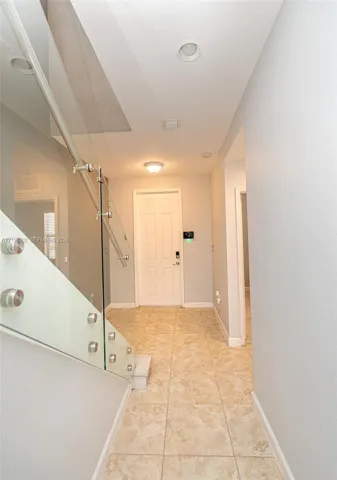 Foyer featuring tile flooring, glass panel railing with stainless steel standoffs, and recessed ceiling lighting