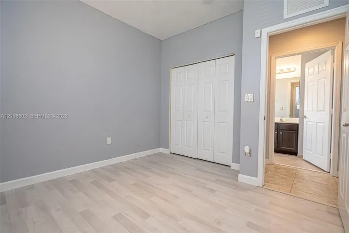 Room featuring wood-finish flooring, neutral wall tones, and a double-door closet
