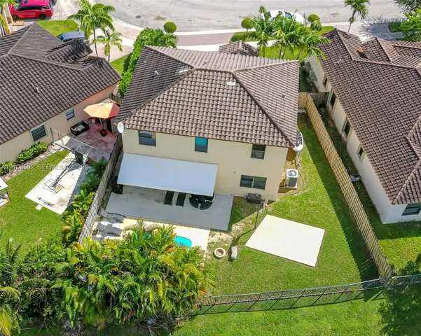 Two-story residence featuring a tile roof, covered rear patio, fenced backyard, swimming pool, and concrete hardscaping