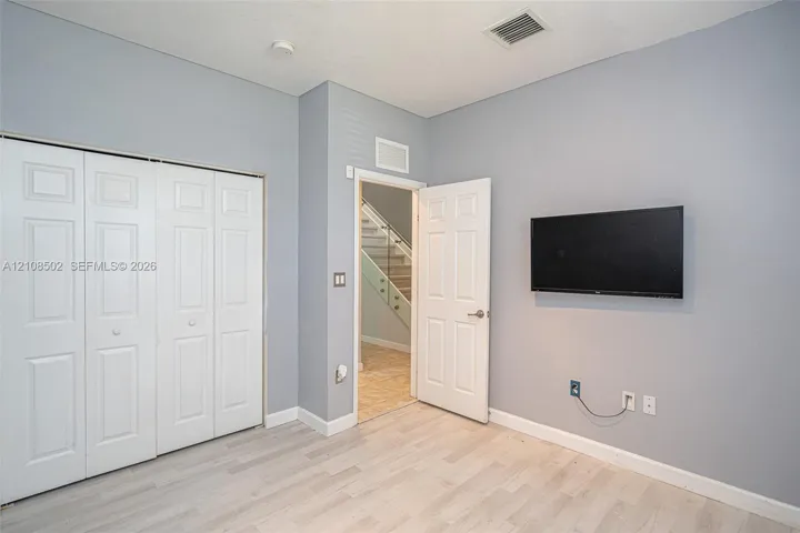 Neutral-toned interior space featuring light wood-finish flooring, four-panel closet doors, and solid-core interior​​‌​​​​‌​​‌‌​‌‌​​​‌‌​‌​‌​‌​​​‌​​ doors