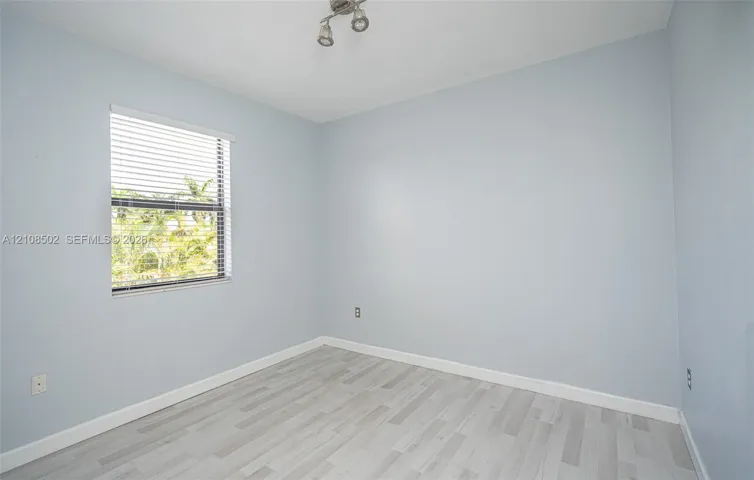 Neutral-toned interior featuring wood-finish flooring, a single window with horizontal blinds, and a multi-directional track light fixture