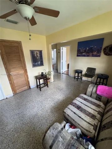 Terrazzo flooring, louvered wood closet door, and a ceiling-mounted fan with integrated light fixture