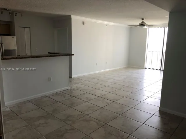 Open floor plan featuring tile flooring, a kitchen pass-through counter, ceiling fan, and sliding glass door access to a balcony