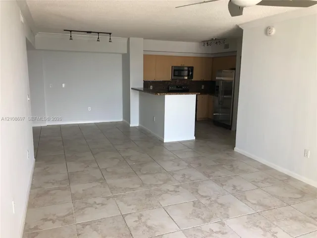 Open-concept interior featuring large-format tile flooring, flat-panel cabinetry, stone countertops, stainless steel appliances, and track lighting
