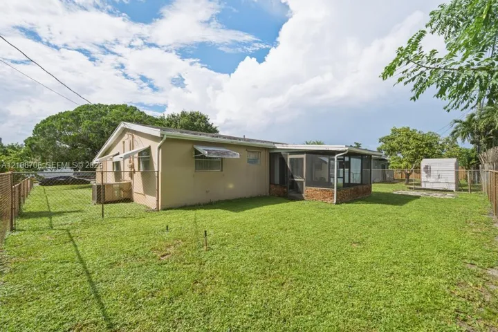 Expansive backyard featuring a fenced perimeter, a screened-in patio, and mature landscaping
