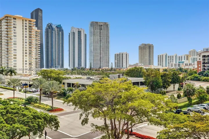 Urban landscape featuring high-rise buildings, mature palm trees, dense foliage, and paved thoroughfares