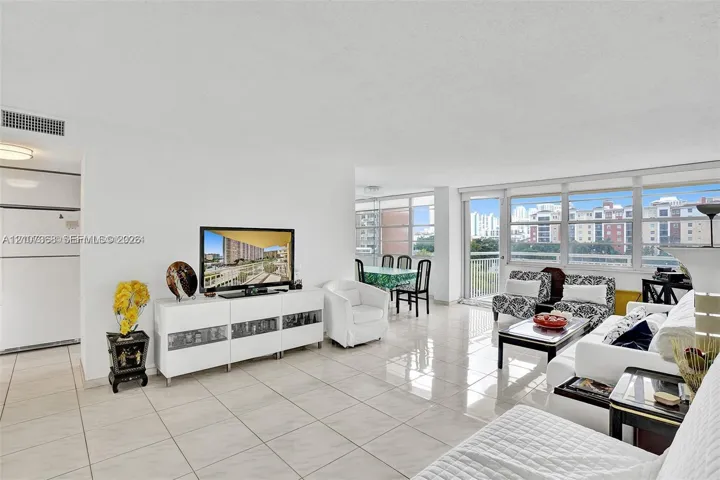 Open-concept interior featuring large-format tile flooring, an expansive wall of floor-to-ceiling windows, and access to a private balcony