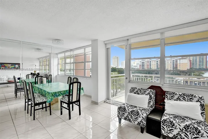 Light-filled interior featuring expansive floor-to-ceiling windows, polished tile flooring, mirrored wall accents, and a private balcony