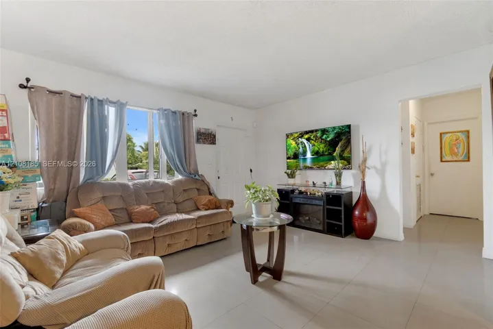Living area featuring large windows with natural light, neutral wall-to-wall tile flooring, and a textured ceiling
