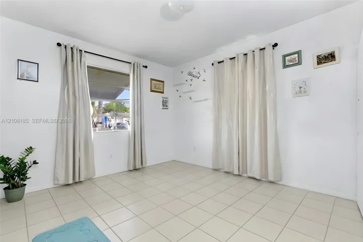 Room featuring neutral tile flooring, dual windows with wall-mounted rods, and overhead flush-mount lighting