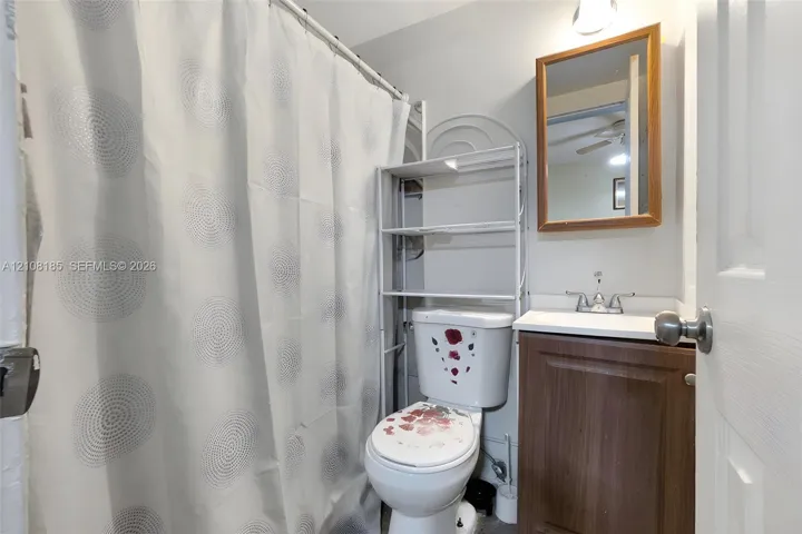 Bathroom featuring a wood-finish vanity cabinet, white sink basin, metallic dual-handle faucet, and wall-mounted wooden-framed mirror